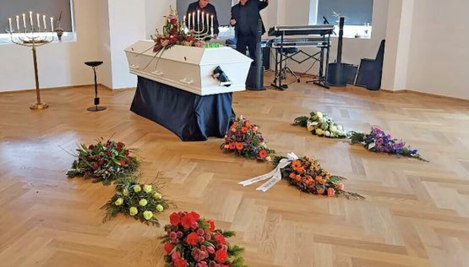 Kisten var udover blomster også udstyret med navneskilt og Leos western-pistol i hylsteret. I baggrunden ses Thomas Ehrenreich og Kim Karmark Petersen, som Sussi spiller med nu. De tog sig af musikken under og efter bisættelsen. (Foto: Privat) Kisten var udover blomster også udstyret med navneskilt og Leos western-pistol i hylsteret. I baggrunden ses Thomas Ehrenreich og Kim Karmark Petersen, som Sussi spiller med nu. De tog sig af musikken under og efter bisættelsen. (Foto: Privat)